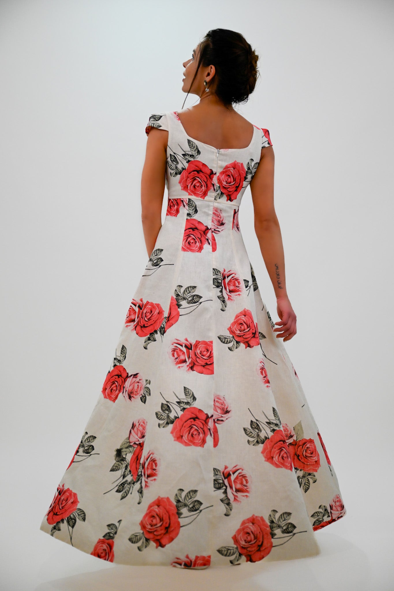 Woman wearing a floral dress with red roses on a white background